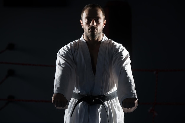 Il giovane che pratica il suo karate muove la cintura nera del kimono bianco