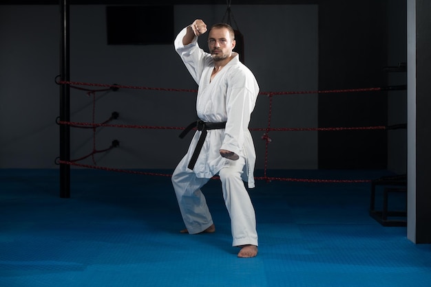 Il giovane che pratica il suo karate muove la cintura nera del kimono bianco