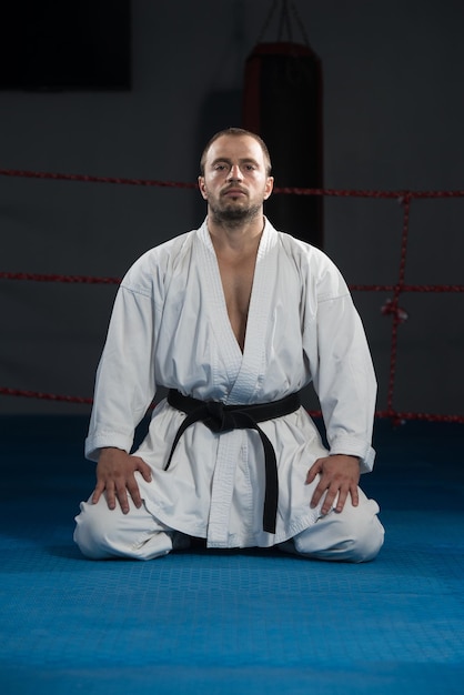 Il giovane che pratica il suo karate muove la cintura nera del kimono bianco