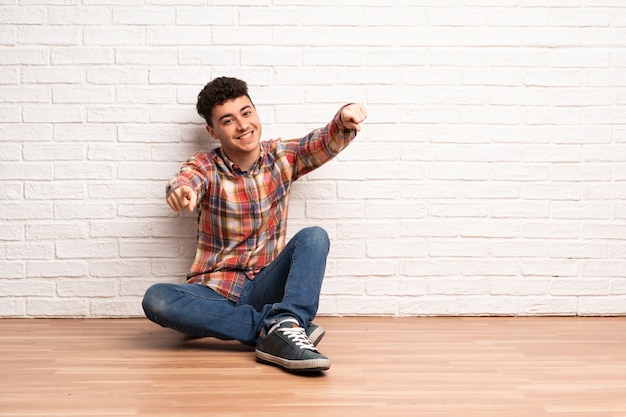 Il giovane che si siede sul pavimento indica il dito voi mentre sorride