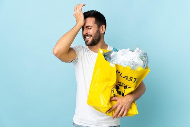 Il giovane che tiene un sacchetto pieno di bottiglie di plastica da riciclare isolato sulla parete blu ha realizzato qualcosa e intende la soluzione