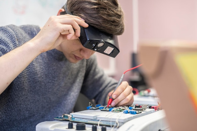 Il giovane con gli occhiali zoom speciali lavora con il chip elettronico al silicio b