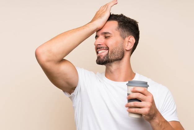 Il giovane con la barba che tiene un caffè da asporto sopra la parete blu isolata ha realizzato qualcosa e intendendo la soluzione