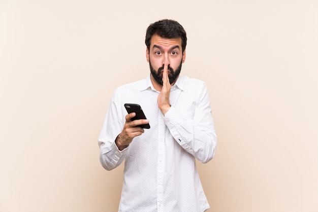 Il giovane con la barba che tiene un cellulare tiene insieme la palma. La persona chiede qualcosa