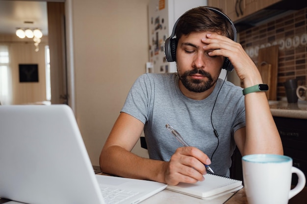 Il giovane concentrato indossa le cuffie studiando online