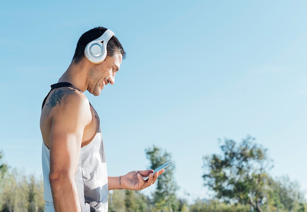 Il giovane corridore dell'atleta con i caschi sorride mentre guarda il cellulare