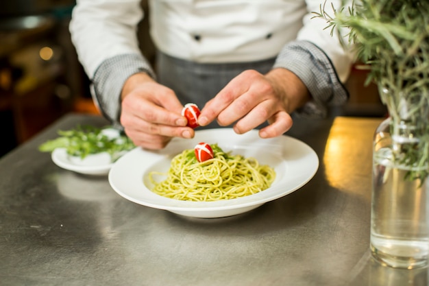 Il giovane cuoco serve e decora gli spaghetti