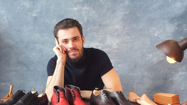 Il giovane designer di scarpe che esamina la macchina fotografica mostra il suo lavoro