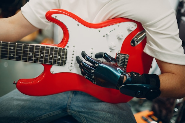 Il giovane disabile con la mano protesica artificiale suona la chitarra elettrica al negozio