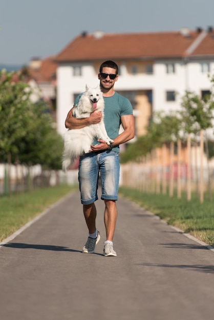 Il giovane e lo spitz tedesco camminano nel parco tiene il cane al guinzaglio