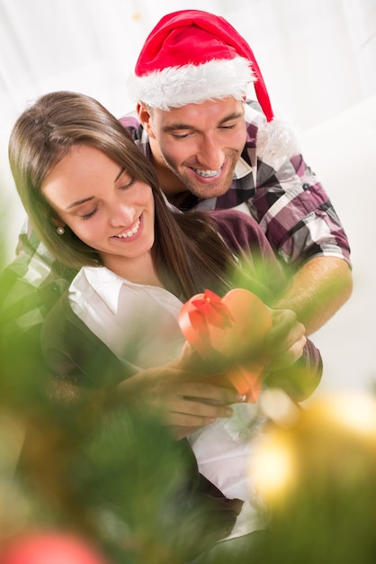 Il giovane fa un regalo di Natale alla sua ragazza. È felice mentre apre la confezione regalo.