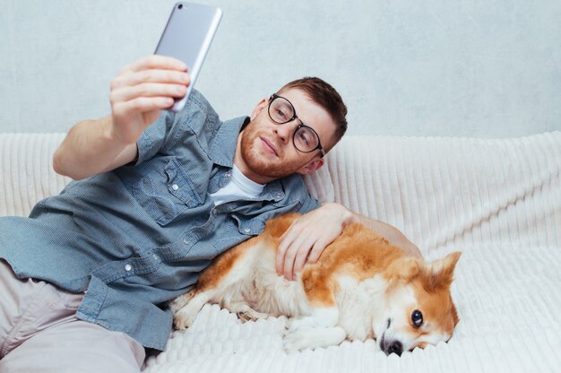 Il giovane fa un selfie con un cane al telefono a casa