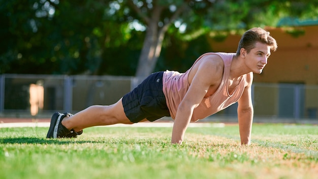 Il giovane fare muscolare dell'uomo spinge aumenta sullo stadio