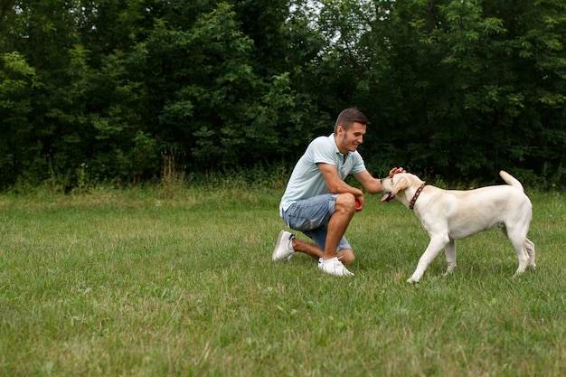 Il giovane felice sta giocando con il cane Labrador