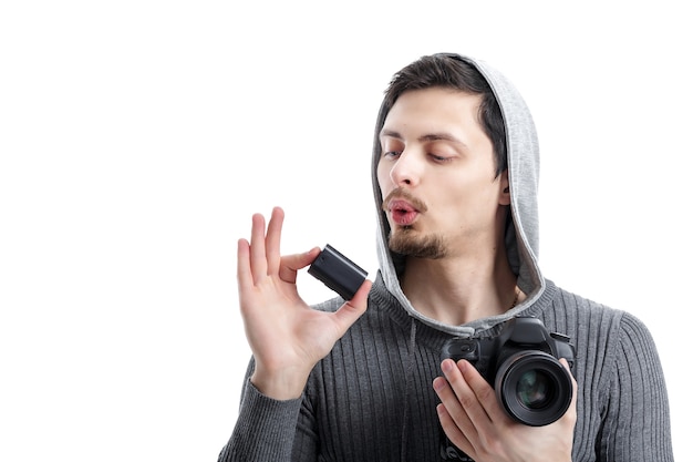 Il giovane fotografo tiene la batteria per la fotocamera digitale DSLR è