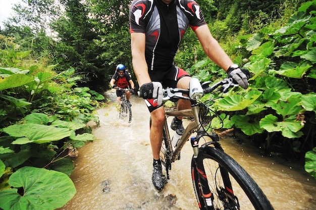 il giovane guida la mountain bike sul fiume d'acqua