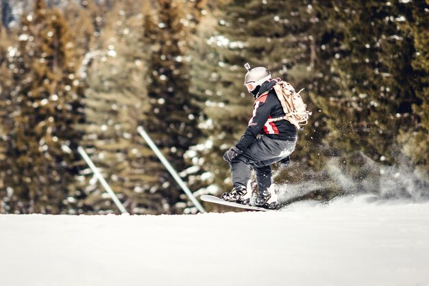 Il giovane guida lo snowboard e si gode una giornata invernale ghiacciata sui pendii delle montagne.