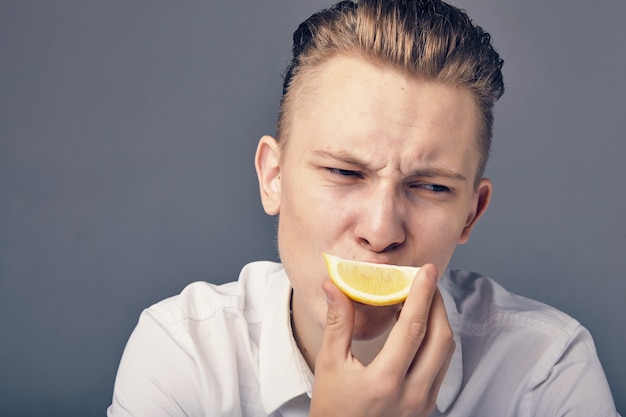 Il giovane ha un'emozione acida mentre assaggia un limone