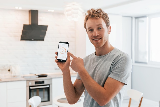 Il giovane in abiti casual è al chiuso controllando la tecnologia della casa intelligente