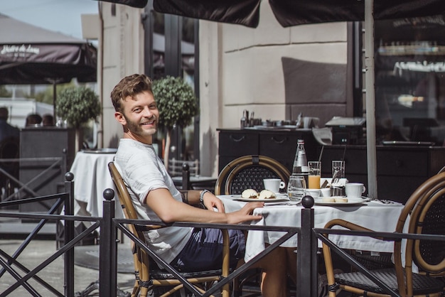 il giovane in un caffè estivo sulla terrazza fa colazione