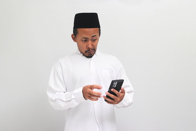 Il giovane indonesiano vede contenuti inappropriati sul suo telefono isolato su sfondo bianco