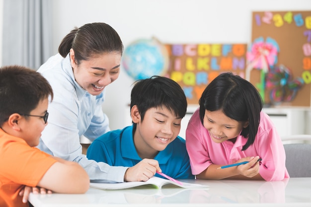 Il giovane insegnante asiatico aiuta i giovani scolari in classe.