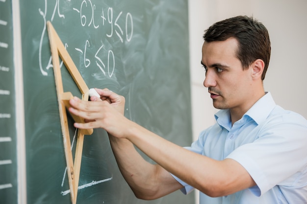 Il giovane insegnante o studente disegna il triangolo su una lavagna con la formula