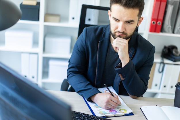 Il giovane lavora in ufficio alla scrivania di un computer con documenti.