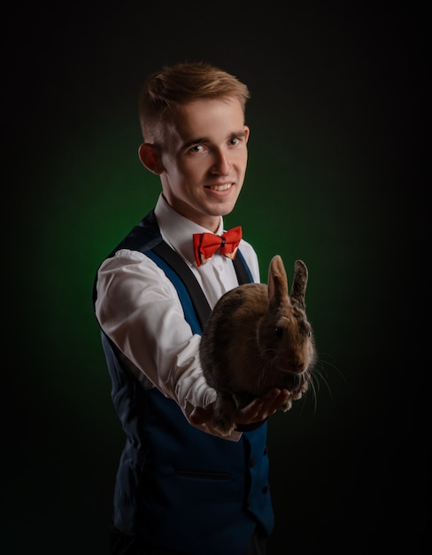 Il giovane mago illusionista che tiene un cappello con un coniglio