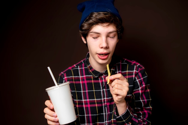 Il giovane maschio mangia patate fritte gratis con soda bb