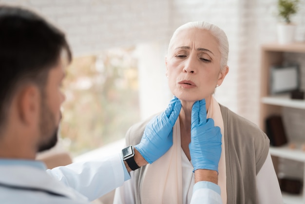 Il giovane medico controlla i linfonodi della donna anziana.