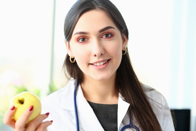 Il giovane medico sorridente della donna tiene la mela