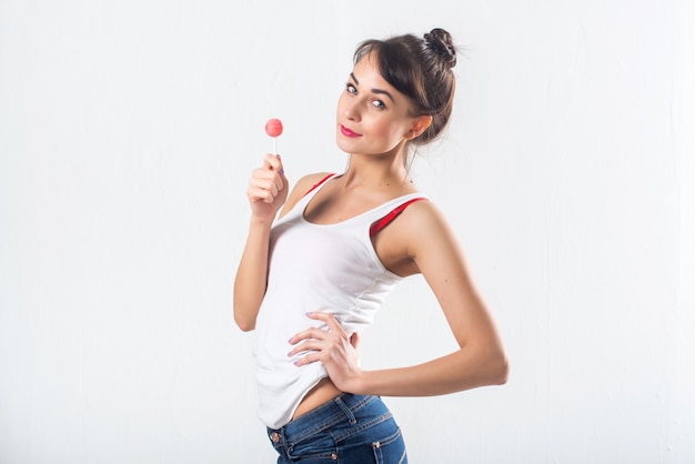 Il giovane modello castana con la lecca-lecca che posa lo studio ha sparato su fondo bianco, non isolato