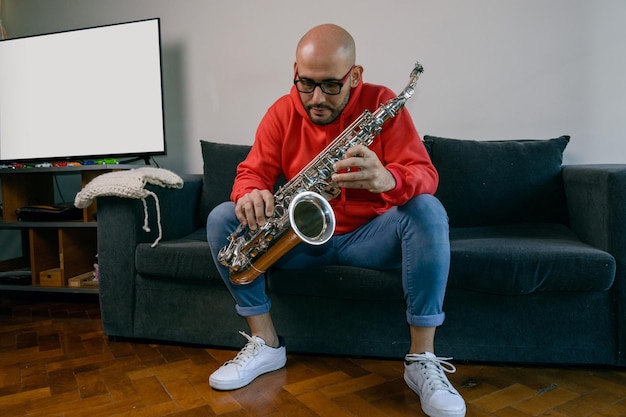 il giovane musicista latino che studia a casa tiene il suo sassofono e sta pensando a come fare l'accordo