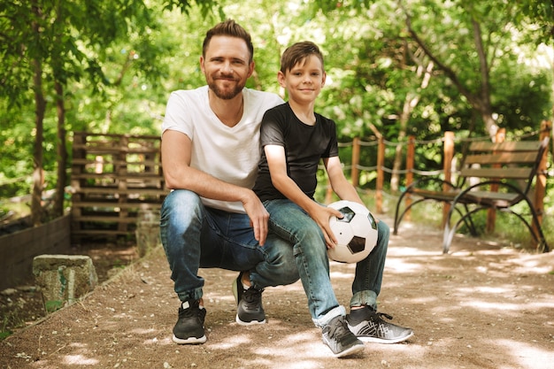 Il giovane padre felice si diverte con il suo piccolo figlio con il calcio