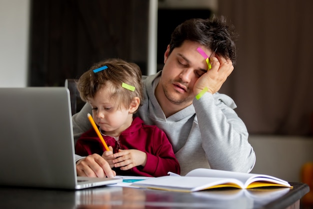 Il giovane padre lavora al computer a casa con un bambino