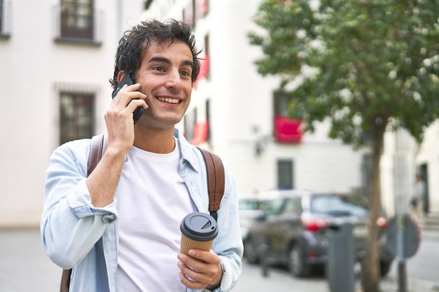 Il giovane padroneggia l'arte del multitasking con un caffè da asporto in mano e una telefonata produttiva