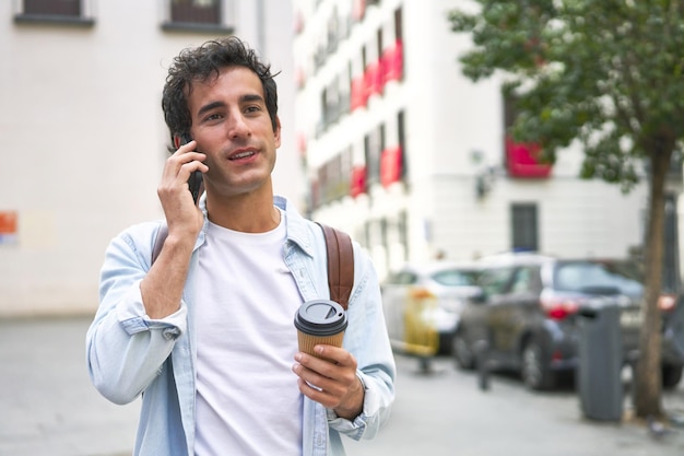 Il giovane padroneggia l'arte del multitasking con un caffè da asporto in mano e una telefonata produttiva