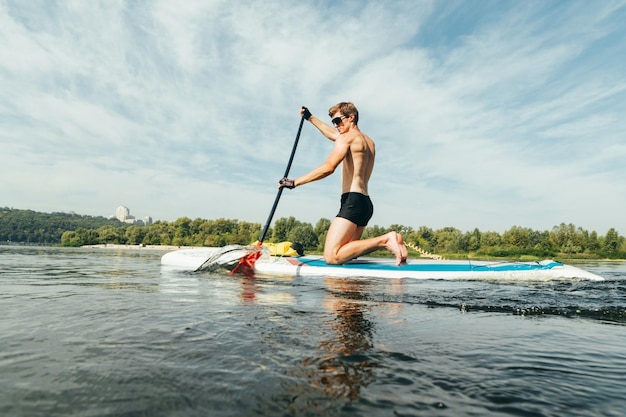 Il giovane pagaia a bordo del sup in una giornata di sole