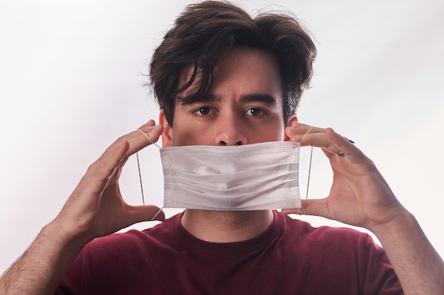 Il giovane passa mettere la nuova maschera del respiratore per la copertura del naso e della bocca nel tempo di quarantena del virus. Prima protezione. Concetto di assistenza sanitaria. Avvicinamento. Vista frontale.