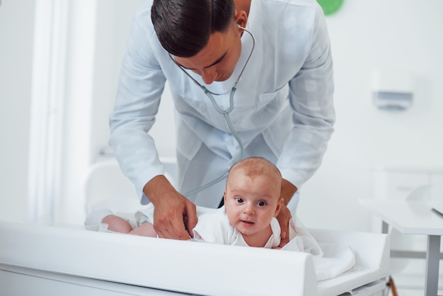 Il giovane pediatra è con il piccolo bambino nella clinica durante il giorno.