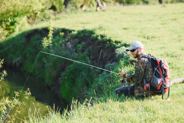 Il giovane pescatore pesca vicino al fiume. Il concetto di attività all'aperto e pesca