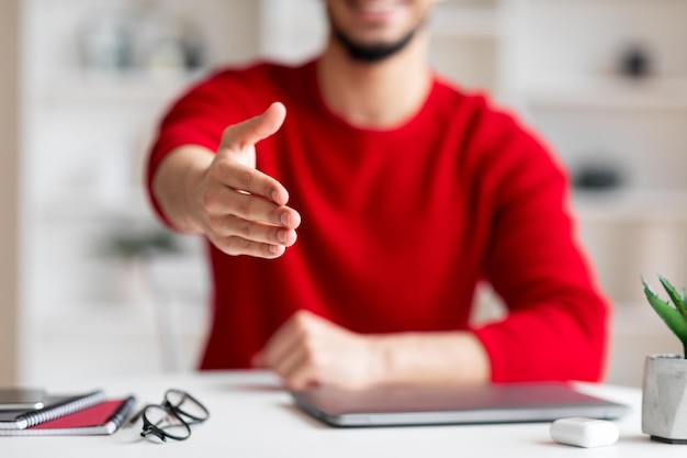 Il giovane ragazzo arabo felice e amichevole dà il benvenuto alla telecamera sul posto di lavoro nell'interno dell'ufficio domestico