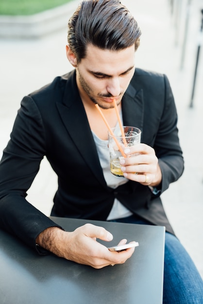 Il giovane ragazzo italiano che beve mentre controlla è smartphone