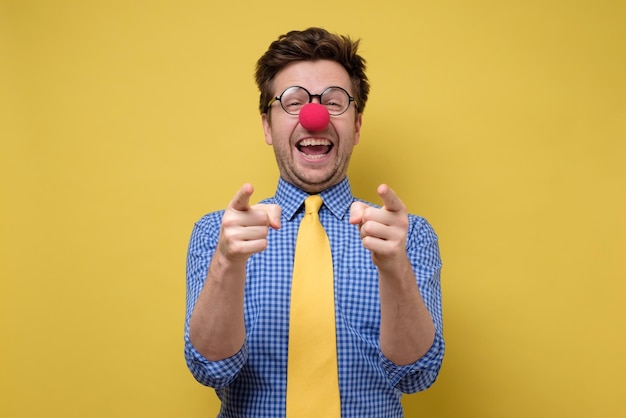 Il giovane ragazzo ridente si è vestito come un clown che punta il dito verso la telecamera