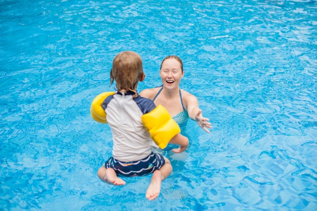 Il giovane ragazzo salta nell'acqua della piscina