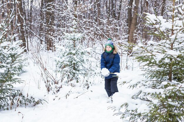 Il giovane ragazzo sveglio gioca con la neve, si diverte, sorride. Adolescente a winter park. Stile di vita attivo, inverno