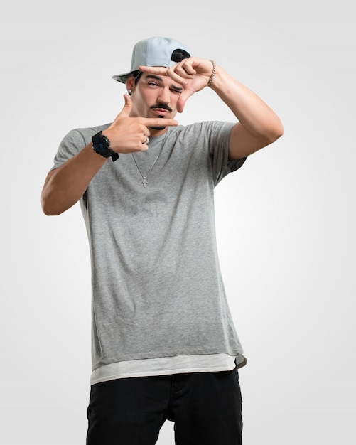 Il giovane rapper fa una cornice con le mani, cercando di mettere a fuoco come se fosse una macchina fotografica