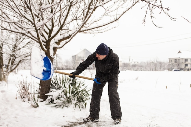 Il giovane rimuove la neve vicino alla casa suburbana