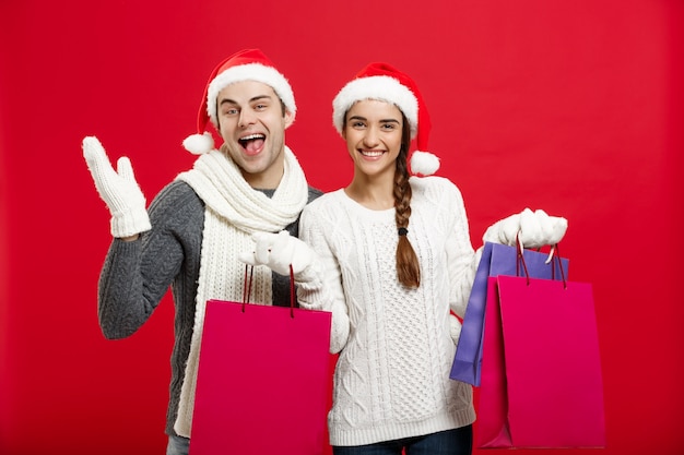 Il giovane sacchetto di acquisto attraente della tenuta delle coppie gode di di comperare e di celebrare nel giorno di Natale.